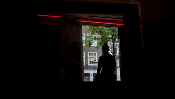 Una prostituta espera clientes detrás de una ventana en el barrio rojo de Ámsterdam. (Foto de Kenzo TRIBOUILLARD / AFP)