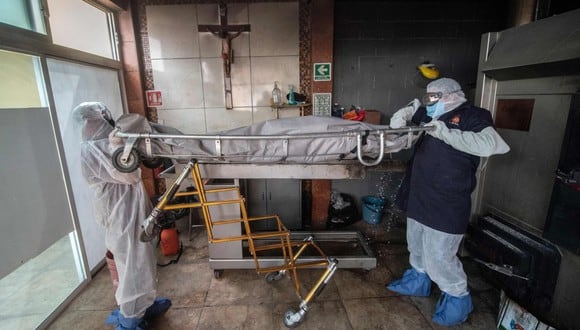 Trabajadores de la morgue mueven el cuerpo de una víctima de COVID-19 en un crematorio en Cuautitlan Izcalli, México. (AFP/PEDRO PARDO).