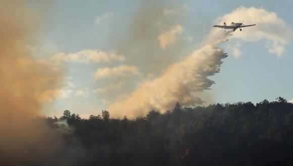 Un avión de extinción de incendios vierte agua sobre un gran incendio forestal cerca de la Ruta 40, a unos 12 km de Paraje Villegas y 60 km al sur de Bariloche, Provincia de Río Negro, Argentina, el 13 de enero de 2022. (Foto referencial: Francisco RAMOS MEJIA / AFP)