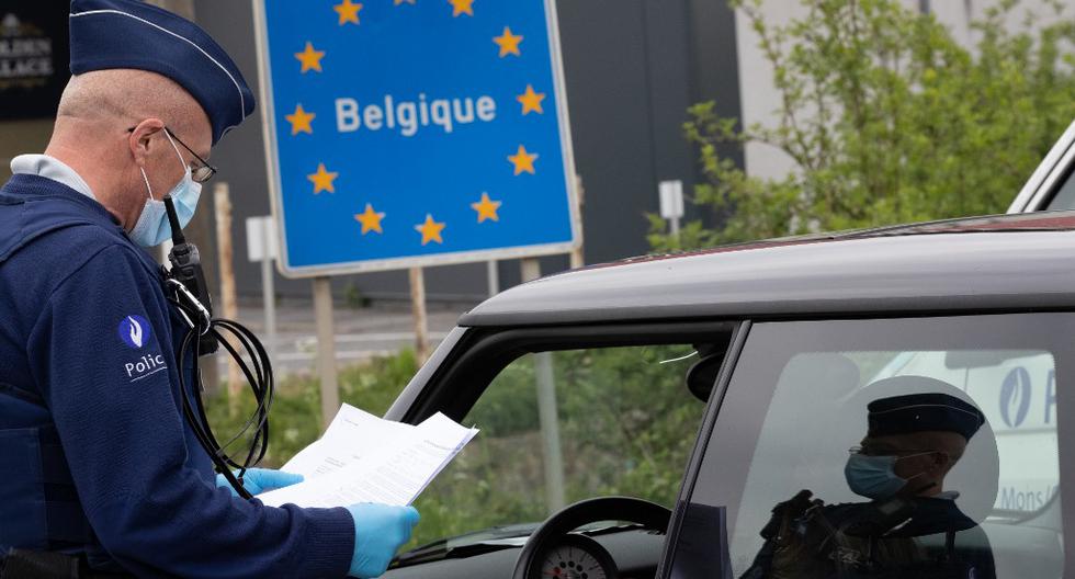 Un oficial de policía belga controla los documentos de una persona en un automóvil en la frontera entre Bélgica y Francia durante una patrulla policial en Quevy, haciendo cumplir las reglas de distanciamiento social. (BENOIT DOPPAGNE / AFP)