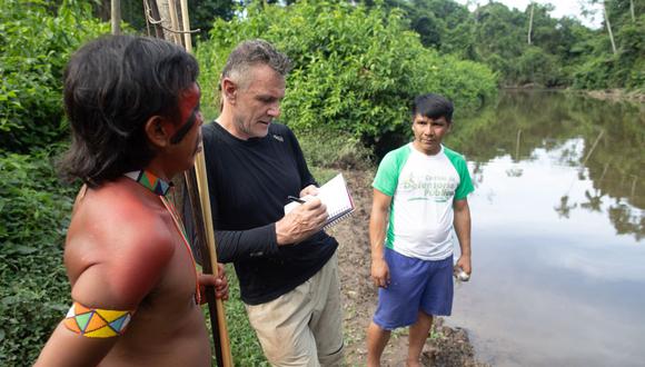 El veterano corresponsal extranjero Dom Phillips (centro) habla con dos hombres indígenas en Aldeia Maloca Papi,  estado de Roraima, Brasil, el 16 de noviembre de 2019. (Foto de Joao LAET / AFP)