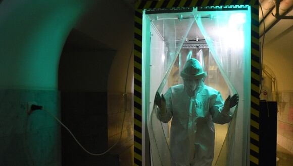 Un trabajador médico que usa un equipo de protección PPE camina a través de una cabina de desinfección en la unidad COVID-19 del Hospital Mariinsky en San Petersburgo. (Foto: Olga MALTSEVA / AFP)