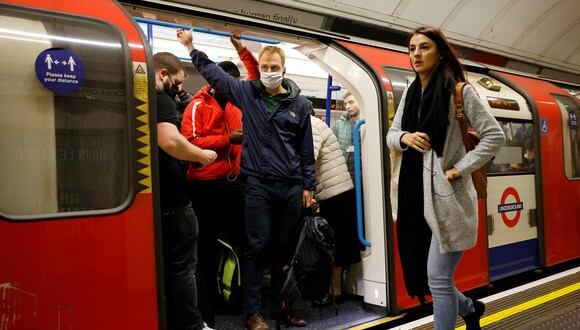 Los viajeros, algunos con cubiertas faciales para ayudar a prevenir la propagación del coronavirus, salen de una estación de tren subterráneo en Londres el 20 de octubre de 2021. (Foto: Tolga Akmen / AFP)