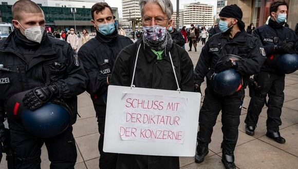 Un hombre que exhibe una pancarta que dice: "No más dictadura de corporaciones" es rechazado por agentes de policía durante una manifestación contra las medidas anti-Coronavirus en Berlín. (Foto: John MACDOUGALL / AFP)