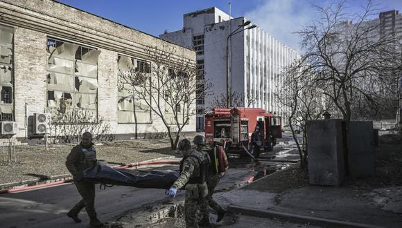 / Miembros del servicio militar de emergencia retiran el cuerpo de un militar ucraniano muerto en el área de un instituto de investigación, parte de la Academia Nacional de Ciencias de Ucrania, después de un ataque, en el noroeste de Kiev, el 22 de marzo de 2022. (Foto de Aris Messinis / AFP)