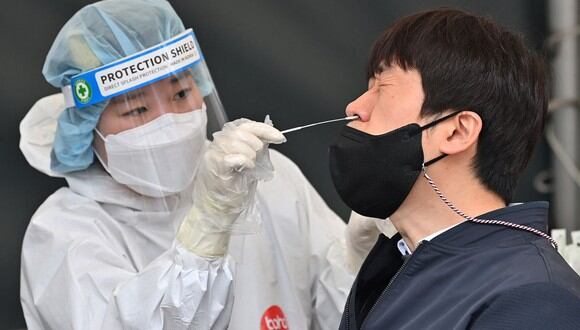 Una trabajadora de la salud toma una muestra de hisopo nasal de un hombre en un centro de pruebas de coronavirus Covid-19 en Seúl, Corea del Sur, el 17 de marzo de 2022. (Jung Yeon-je / AFP).