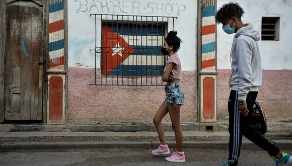 Jóvenes con mascarillas como medida de precaución contra la propagación del nuevo coronavirus, COVID-19, caminan en La Habana el 22 de febrero de 2021. (Foto: Yamil LAGE / AFP)