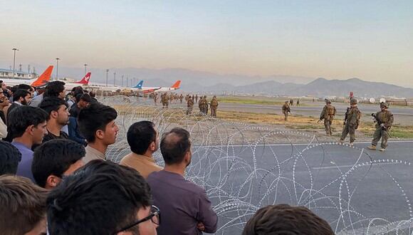 Un grupo de afganos se agolpan en el aeropuerto mientras los soldados estadounidenses montan guardia en Kabul el 16 de agosto de 2021. (Foto de Shakib Rahmani / AFP)