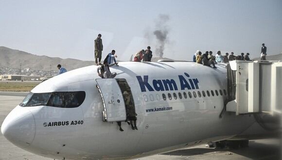 Los afganos se suben a un avión mientras esperan en el aeropuerto de Kabul tratando de huir de los talibanes en Afganistán. (Foto de Wakil Kohsar / AFP)