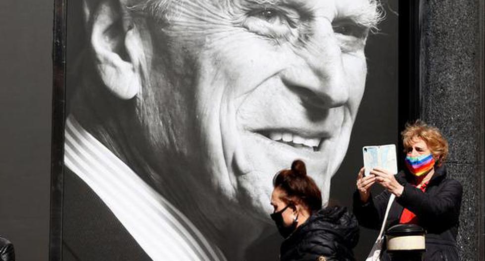 Una mujer se toma una selfie afuera de un supermercado que tiene un cartel con el príncipe Felipe de Gran Bretaña, duque de Edimburgo. (Foto: Adrian DENNIS / AFP).