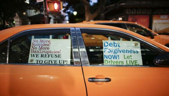 Los carteles se muestran en las ventanas de una cabina amarilla, ya que los conductores asisten a un rally que exige perdón de deuda para los taxistas. (Foto: Kena Betancur / AFP)