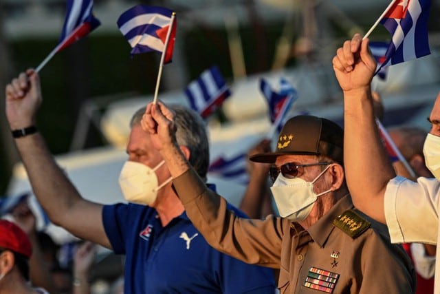 El presidente cubano Miguel Díaz-Canel (izquierda) y el expresidente Raúl Castro (derecha) ondean banderas cubanas durante un acto de reafirmación revolucionaria en La Habana, el 17 de julio de 2021. (YAMIL LAGE / AFP).