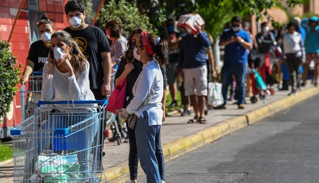 Supermercados, farmacias y locales de servicios públicos de siete comunas en Santiago amanecieron este jueves con grandes aglomeraciones de personas apuradas por hacer compras o trámites, antes del comienzo de una cuarentena total esta noche por el coronavirus. (AFP).
