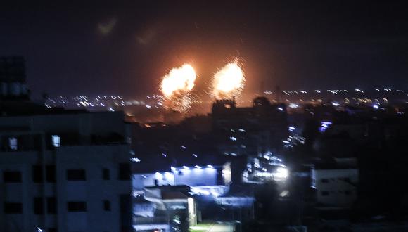 Las explosiones iluminan el cielo nocturno sobre los edificios en la ciudad de Gaza mientras las fuerzas israelíes bombardean el enclave palestino, a principios del 16 de junio de 2021 (Foto de Mahmud hams / AFP).
