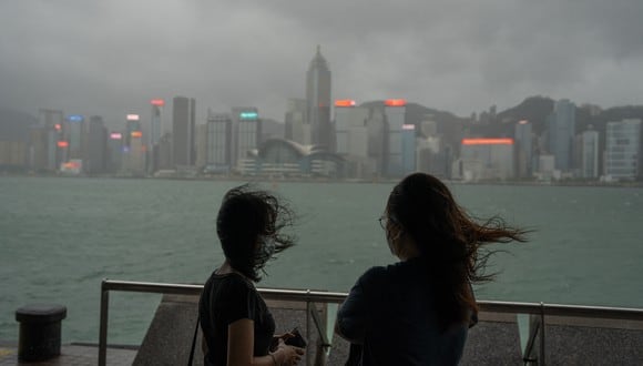 La gente se reúne en medio de un fuerte viento en un paseo junto al puerto de Victoria cuando el tifón Chaba pasa por Hong Kong el 2 de julio de 2022. (Foto de Bertha WANG / AFP)