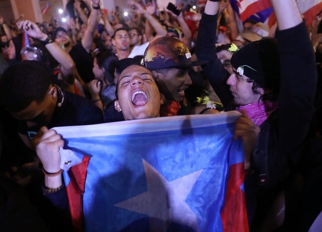 Apenas terminó de difundirse el video, se escuchó la algarabía y los "olé olé olé" de cientos de puertorriqueños que desde la tarde protestaban a las puertas de La Fortaleza, la casa de gobierno en San Juan. (Fotos: AFP)