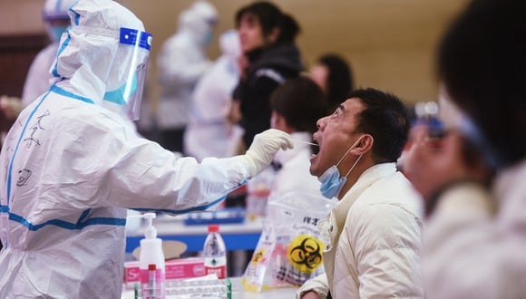 Un trabajador médico toma una muestra de un hisopo de un trabajador de servicios para hacerle la prueba del Covid-19 en Hangzhou, en la provincia oriental china de Zhejiang. (Foto: AFP)