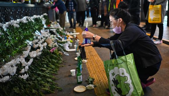 Una mujer hace una ofrenda, en homenaje a los muertos en una estampida de Halloween el 29 de octubre, en un monumento improvisado fuera de la estación de metro de Itaewon en el distrito de Itaewon en Seúl el 30 de octubre de 2022. (Foto de Anthony WALLACE / AFP)