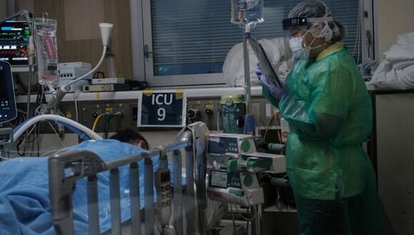 Un trabajador médico mira afuera desde una sala de presión negativa en busca de un paciente con coronavirus Covid-19 en un ventilador mecánico en el área designada por Covid-19 de la unidad de cuidados intensivos (UCI). (Foto: Yasuyoshi CHIBA / AFP)