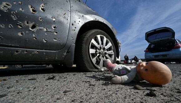 Una muñeca abandonada junto a un automóvil acribillado a balazos en Irpin, al norte de Kiev. (Foto: Sergei SUPINSKY / AFP)