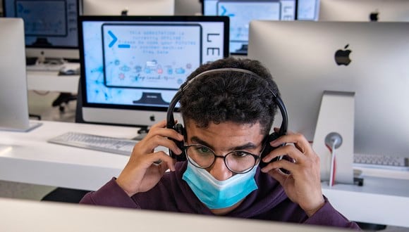 Un estudiante, vestido con una máscara debido a la pandemia del coronavirus COVID-19, ajusta sus auriculares mientras usa una computadora en una sala de laboratorio en el centro de capacitación en tecnología de la información "1337" en la ciudad de Khouribga, en el centro de Marruecos. (Foto de FADEL SENNA / AFP)