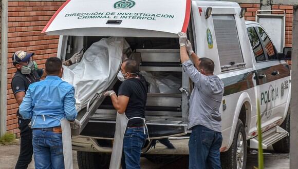 Imagen referencial. Policías descargan los cadáveres de víctimas de una masacre presuntamente a manos de grupos armados en el municipio colombiano de Arauca. (AFP/Daniel Fernando Martinez).