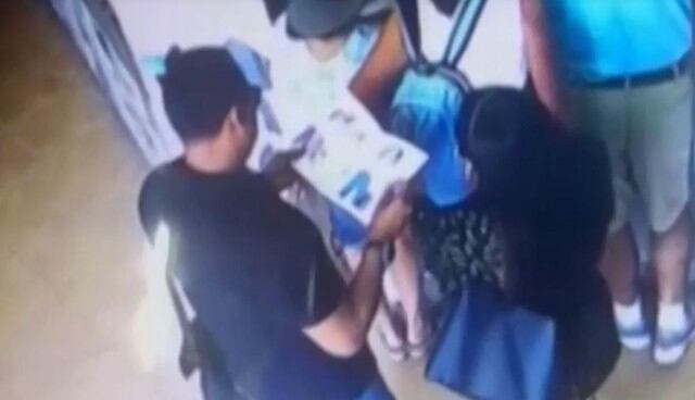 Pareja de ladrones usan revista para abrir mochila y robar celular a turistas argentinos. Foto: Captura de América Noticias