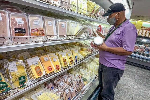 Un hombre escoge productos en una nevera de carnes frías en un supermercado de Caracas (Venezuela).  (EFE/ Miguel Gutiérrez).
