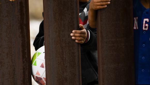 Los niños se aferran a una cerca del muro fronterizo del lado mexicano de la frontera entre Estados Unidos y México entre Nuevo México y el estado de Chihuahua el 9 de diciembre de 2021 en Sunland Park, Nuevo México. (Foto de Patrick T. FALLON / AFP)