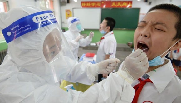 Un trabajador sanitario toma una muestra de un hisopo a un estudiante para saber si está contagiado del coronavirus COVID-19 antes de que las escuelas abran en la provincia de Hebei, en el norte de China. (Foto de STR / AFP).