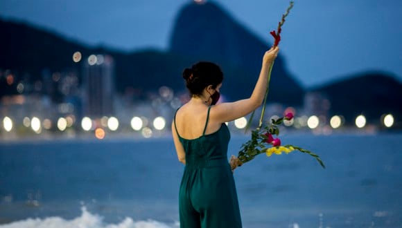 Una mujer reflexiona antes de arrojar flores a Iemanja, diosa del mar, en la playa de Copacabana en vísperas de Año Nuevo, en Río de Janeiro, Brasil, el 31 de diciembre de 2021. (Foto de Daniel RAMALHO / AFP)