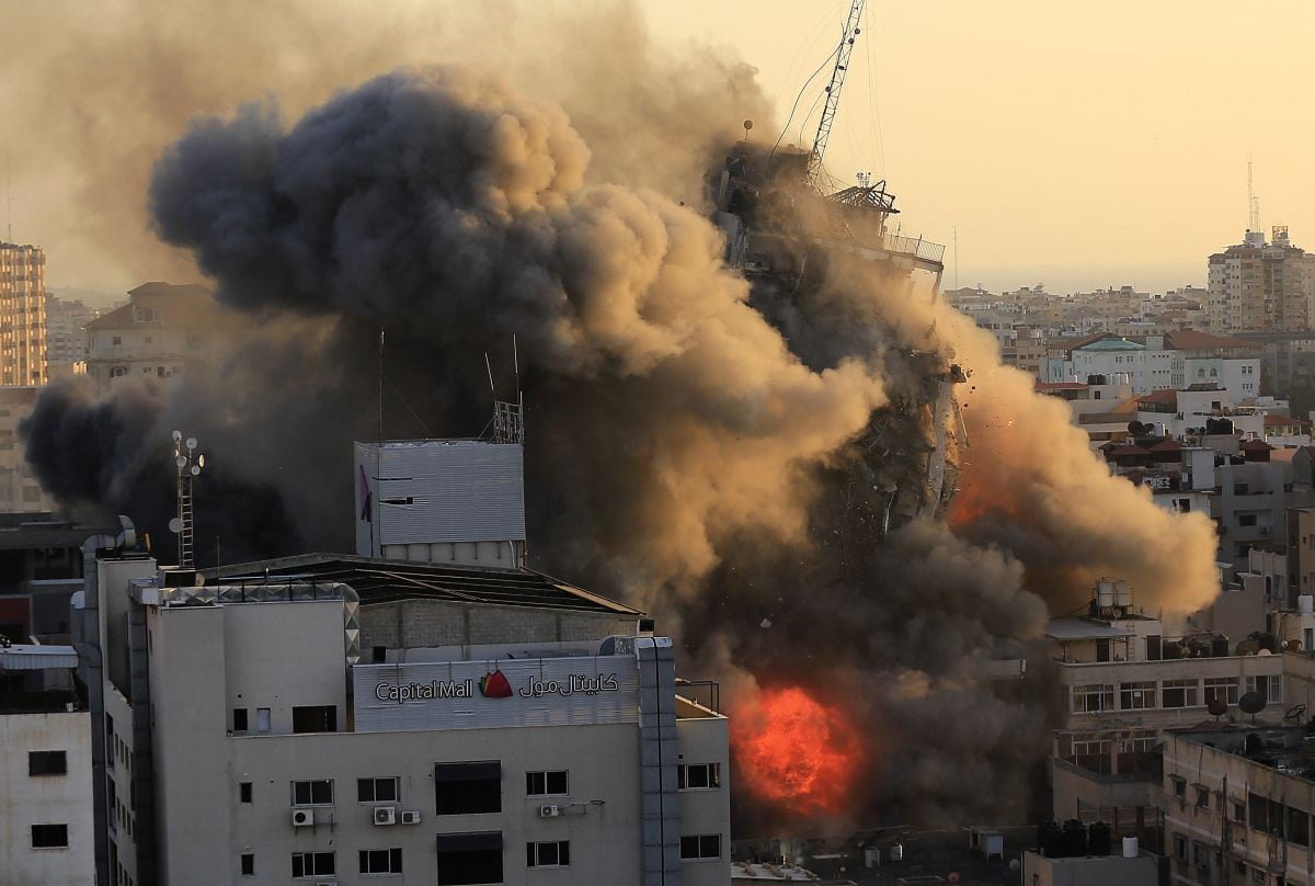El humo y el fuego denso rodean la torre de Al-Sharouk cuando se derrumba durante un ataque aéreo israelí, en la ciudad de Gaza el 12 de mayo de 2021. (QUSAY DAWUD / AFP).