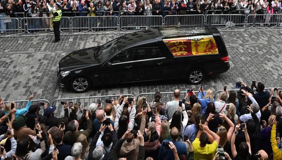 Los miembros del público observan el coche fúnebre que lleva el ataúd de la reina Isabel II, envuelto en el estandarte real de Escocia, mientras se conduce a través de Edimburgo hacia el Palacio de Holyroodhouse, el 11 de septiembre de 2022.  (Foto de Oli SCARFF / AFP)
