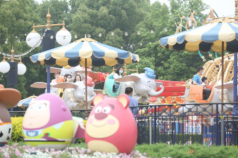 Las personas que usan máscaras protectoras disfrutan de un paseo en el parque temático Disneyland, en Shanghai. (EFE)