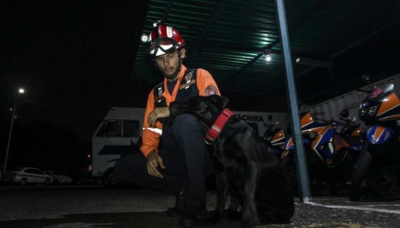 Un miembro de Protección Civil y un perro, parte de un grupo de rescatistas, esperan para salir en un operativo de búsqueda y rescate de miembros de un grupo religioso que continúan desaparecidos en San Cristóbal, estado Táchira, Venezuela el 6 de septiembre de 2022.  (Foto por JOHNNY PARRA / AFP)