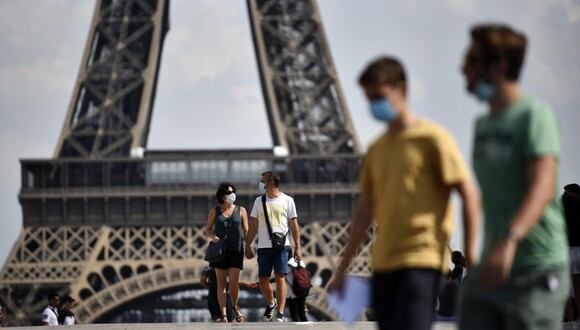 Personas con mascarillas caminan frente a la Torre Eiffel, como parte de las medidas para contener la propagación del coronavirus en París (Francia). (Foto: EFE / Julien de Rosa).