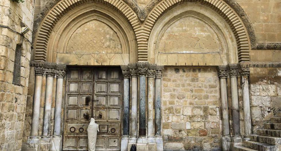 Un peregrino cristiano vestido como Jesucristo se para frente a la puerta cerrada de la Iglesia del Santo Sepulcro en la Ciudad Vieja de Jerusalén el 10 de abril de 2020. (EMMANUEL DUNAND / AFP)