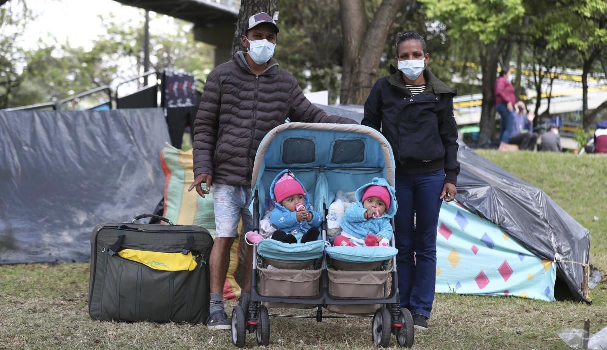 Darwin Herrera, a la izquierda, y su esposa Jennifer Repelo posan con sus gemelas de seis meses y su equipaje en un parque de Bogotá (Colombia). (AP/Fernando Vergara).