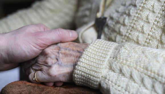 Una mujer, que sufre de la enfermedad de Alzheimer, coge la mano de un pariente en una casa de retiro en Francia. (Foto: Sebastien Bozon/AFP)