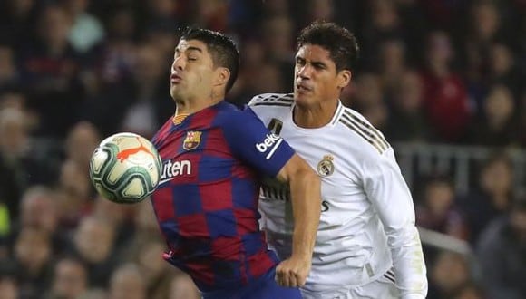 Barcelona's Luis Suarez, left, duels for the ball with Real Madrid's Raphael Varane during a Spanish La Liga soccer match between Barcelona and Real Madrid at Camp Nou stadium in Barcelona, Spain, Wednesday, Dec. 18, 2019. Thousands of Catalan separatists are planning to protest around and inside Barcelona's Camp Nou Stadium during Wednesday's "Clasico". (AP Photo/Emilio Morenatti)