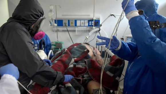 Los trabajadores de salud rodean a un paciente de COVID-19 que llegó a la sala de emergencias, después de intubarlo en la unidad de cuidados intensivos (UCI) del centro médico de San Luis en Soacha. (AFP/Raul ARBOLEDA).