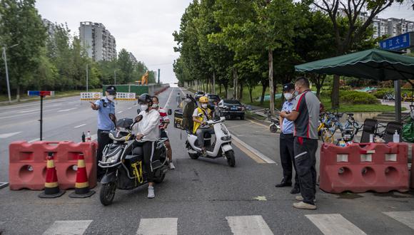 Esta foto tomada el 1 de septiembre de 2022 muestra a policías revisando información en una carretera en medio de restricciones debido a un brote del Covid-19 en Chengdu, en la provincia de Sichuan, suroeste de China. (Foto por CNS / AFP)