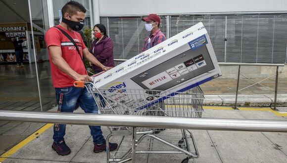 Un hombre empuja un carrito con un televisor. (Foto por Juan BARRETO / AFP).