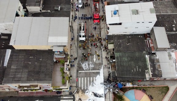 En esta vista aérea, bomberos, policías y rescatistas trabajan en el lugar donde se estrelló una avioneta que dejó dos personas muertas en Guayaquil, Ecuador, el 18 de octubre de 2022. (Foto por Marcos Pin / AFP)