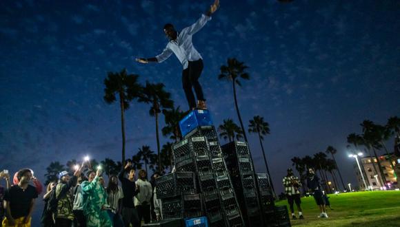 Un hombre está a punto de caer de una pirámide de cajas de leche mientras participa del "Desafío de la Caja de Leche", el 24 de agosto de 2021 en Venice, California. (Foto: Apu GOMES / AFP)