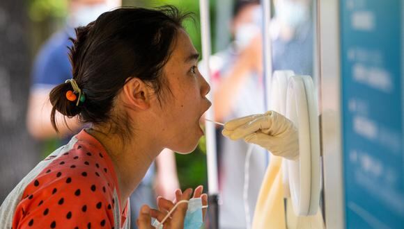 Una mujer se somete a una prueba de muestra de hisopo para detectar el coronavirus Covid-19 en un sitio de recolección de hisopos en el distrito de Pudong de Shanghái el 31 de mayo de 2022. (Foto de LIU JIN / AFP)