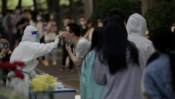 Un trabajador de la salud obtiene una muestra de hisopo de un hombre para realizarle la prueba del Covid-19 en un sitio de recolección de hisopos en Beijing el 27 de mayo de 2022. (Foto de Noel Celis / AFP)