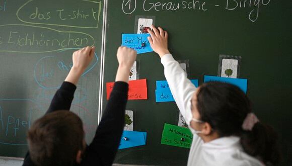 Un alumno de Ucrania y una niña reaccionan frente a una pizarra escolar durante una clase escolar internacional en la escuela integral Max-Ernst (Gesamtschule) en Colonia, Alemania occidental. (Foto: Ina FASSBENDER / AFP)