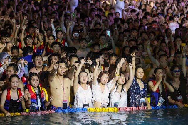 Esta foto tomada el 15 de agosto de 2020 muestra a personas que ven una actuación mientras se refrescan en una piscina en Wuhan, en la provincia central china de Hubei. (Foto: STR / AFP)