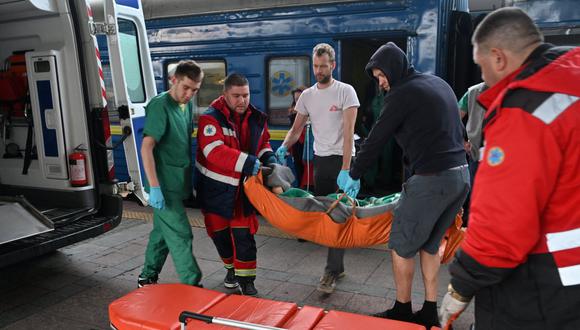 El equipo de ambulancia y los médicos de MSF transfieren a un paciente a una ambulancia en Kiev el 10 de abril de 2022. (Foto de Genya SAVILOV / AFP)